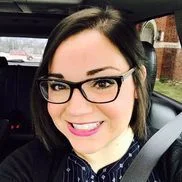 Smiling woman with glasses in car.